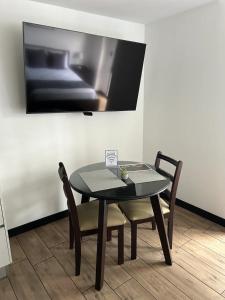 a table with two chairs and a tv on a wall at EÓN 11 - Moderno, vista volcán, aire acondicionado in Guatemala