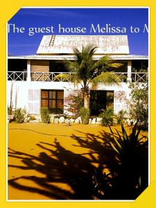 a guest house with a palm tree in front of it at Maison Melissa in Tsivonoabe