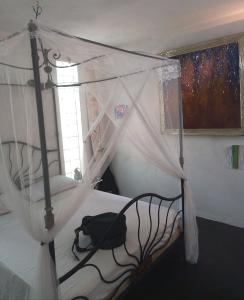 a bedroom with a canopy bed with a bag on it at Maison Melissa in Tsivonoabe