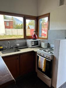 a kitchen with a stove and a sink and two windows at Los radales in Esquel