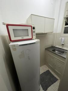 a microwave on top of a refrigerator in a kitchen at Flat Copacabana Posto 4 in Rio de Janeiro