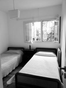 two beds in a room with two windows at Casa a 100 metros del mar, garaje doble in Mar del Plata