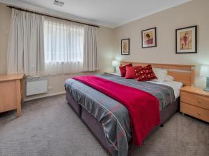 a bedroom with a large bed with red pillows at Wanderers Retreat in Jindabyne