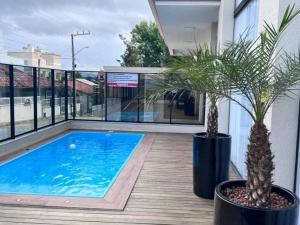 una piscina su un balcone con due piante in vaso di Apartamento, Com Piscina - 350m da Praia de Bombas - 2 Suítes, 6 Pessoas a Bombinhas