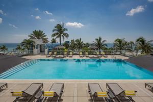 a swimming pool with chairs and the ocean in the background at The Westin Fort Lauderdale Beach Resort in Fort Lauderdale