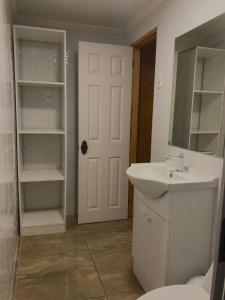 baño con lavabo y puerta blanca en Hostal Riposo, en Los Vilos
