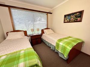 a bedroom with two beds and a window with a window at Grassvale Farms Retreat - Lodge in Lindenow