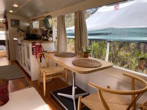 a kitchen with a table and a large window at BUS - Tiny home - 1980s classic with off grid elegance in Faraday