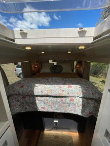 ein Bett auf der Rückseite eines Wohnwagens in der Unterkunft BUS - Tiny home - 1980s classic with off grid elegance in Faraday