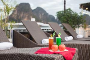 einen Tisch mit Äpfeln und einen Drink auf einer roten Serviette in der Unterkunft Ruby Cruise in Hạ Long