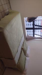 a bed sitting in a room next to a window at Quarto a 10m da praia ao lado de Pubs e Restaurantes in Recife
