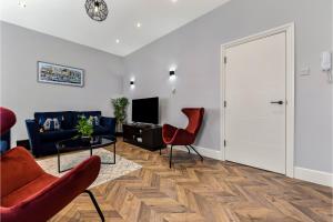 sala de estar con sofá azul y sillas rojas en Welcoming and Radiant - Lovely & Family Friendly!, en Londres