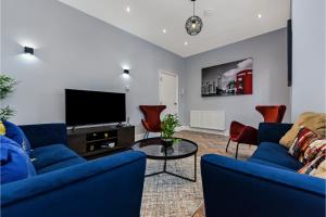 sala de estar con 2 sofás azules y TV en Welcoming and Radiant - Lovely & Family Friendly!, en Londres