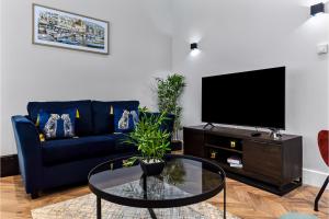 a living room with a blue couch and a tv at Welcoming and Radiant - Lovely & Family Friendly! in London