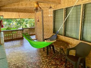 eine grüne Hängematte in einem Zimmer mit Tisch und Stühlen in der Unterkunft Borbon's Treehouse By the Sea in Mambajao