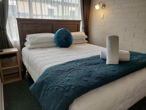 a bedroom with a bed with a blue pillow on it at Colonial on Tay in Invercargill