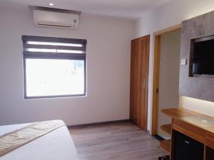 a bedroom with a bed and a tv and a window at Prague Nha Trang in Nha Trang