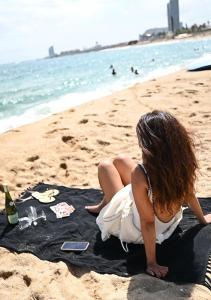 uma mulher de vestido branco sentada na praia em En Calma por el Mediterráneo. em Sant Adria de Besos