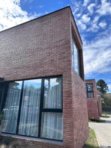 een bakstenen gebouw met grote ramen aan de zijkant bij Duplex Las magnolias Villa allende in Villa Allende