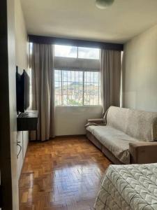 ein Wohnzimmer mit einem Sofa und einem Fenster in der Unterkunft Apartamento BH Centro-Sul in Belo Horizonte