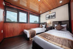 two beds in a room with wooden walls and windows at Ruby Cruise in Ha Long