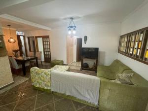 a living room with a green couch and a television at Chácara Cantinho Castanheira a 40 min de SP prox Itu e Sorocaba in Itu
