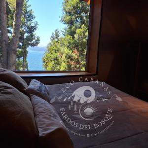a book sitting on a bed in front of a window at Eco Cabañas Fardos del Bosque in San Carlos de Bariloche
