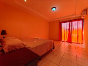 Schlafzimmer mit einem Bett und einem Fenster mit roten Vorhängen in der Unterkunft Casa Céntrica Comayagua in Comayagua