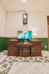 a living room with a television and a clock on the wall at Griyo Kiswo Vacation Home in Lawean