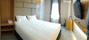1 dormitorio con 1 cama blanca y TV en D'Ninety Six Inn Hotel Gunungkidul, en Siyonokulon