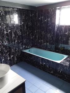ein Bad mit einer Badewanne in einer schwarzen Wand in der Unterkunft 10Pax Deluxe Apartment, CloudView Snoopy Theme, Golden Hills Resort Genting, Formerly Known as Amber Court in Genting Highlands