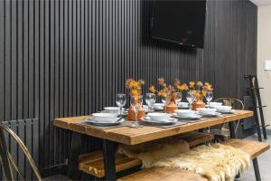 a wooden table with plates and vases of flowers at Modern & Funky 3-BR Duplex with Games Room & Sauna in London