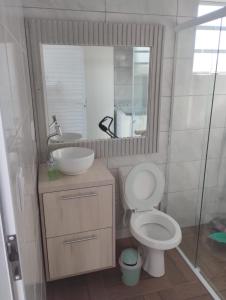 uma casa de banho com um WC, um lavatório e um espelho. em Casa em imbé em Imbé