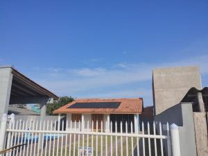 a white picket fence with a house behind it at Casa em imbé in Imbé