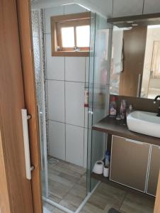 a bathroom with a glass shower and a sink at Casa em imbé in Imbé