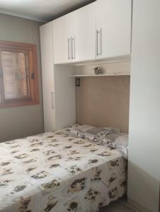 a bedroom with a bed and white cabinets at Casa em imbé in Imbé