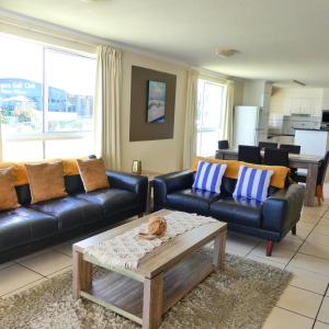 sala de estar con sofás de cuero negro y mesa de centro en Bargara Blue Resort, en Bargara