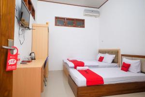 a room with two beds and a desk in it at RedDoorz Syariah near Alun Alun Temanggung in Temanggung