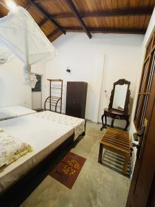 1 dormitorio con 2 camas, espejo y silla en Royal Resort en Weligama