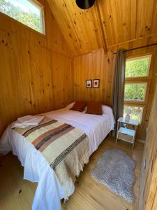a bedroom with a bed in a wooden cabin at Refugio Río Roberto in Villa Santa Lucía