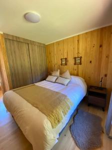 a large bed in a room with wooden walls at Refugio Río Roberto in Villa Santa Lucía