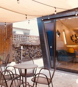 a patio with tables and chairs and a stone wall at Mir Guesthouse in Jeju