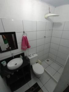 uma casa de banho com um WC, um lavatório e um espelho. em Casa Para Temporada - Cantinho da Cida em Serra