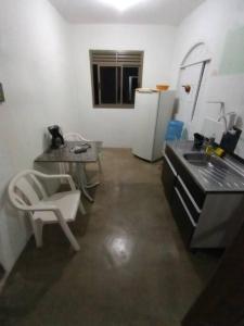a kitchen with a sink and a table and a chair at Casa Para Temporada - Cantinho da Cida in Serra