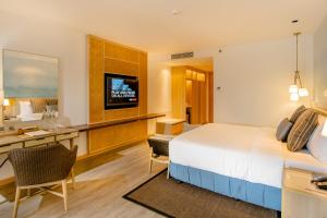 um quarto de hotel com uma cama, uma secretária e uma televisão em Modala Beach Resort em Panglao