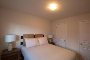 ein Schlafzimmer mit einem weißen Bett und zwei Lampen in der Unterkunft Executive 3 Bedroom townhouse close to the Lake in Hamilton