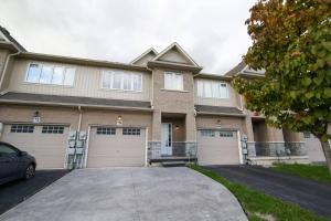 a large house with two garages and a driveway at Executive 3 Bedroom townhouse close to the Lake in Hamilton