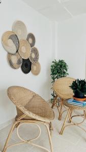 dwa krzesła i stół z kapeluszami na ścianie w obiekcie Casa Gali w mieście Ríohacha
