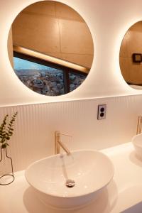 a bathroom with a sink and two circular mirrors at Mir Guesthouse in Jeju