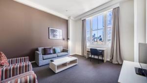 雪梨的住宿－Oaks Sydney Goldsbrough Suites，客厅配有沙发和桌子